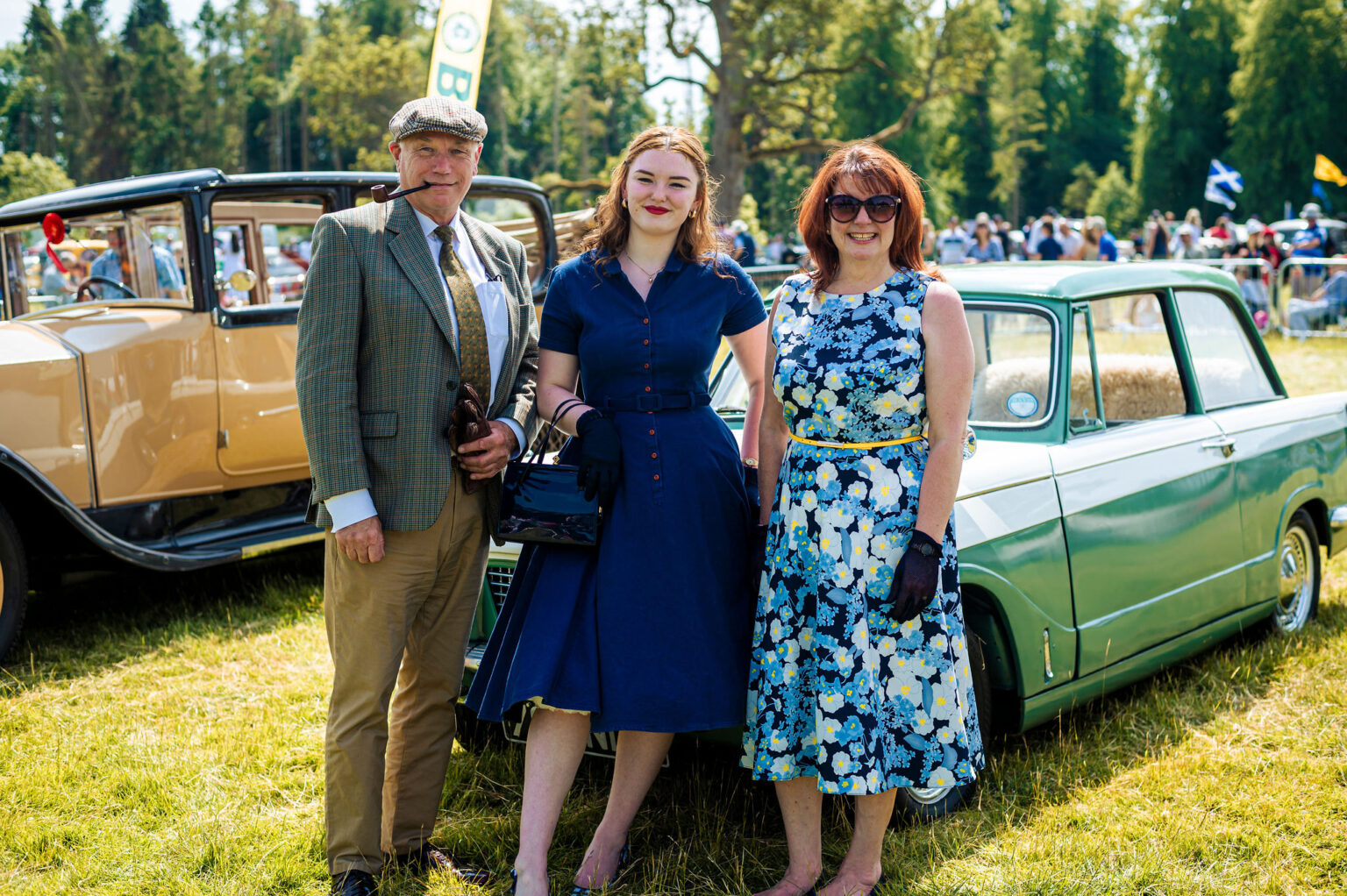 Visitors in period dress beside classic cars